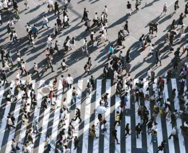 A large crowd of people crossing a zebra crossing in a city